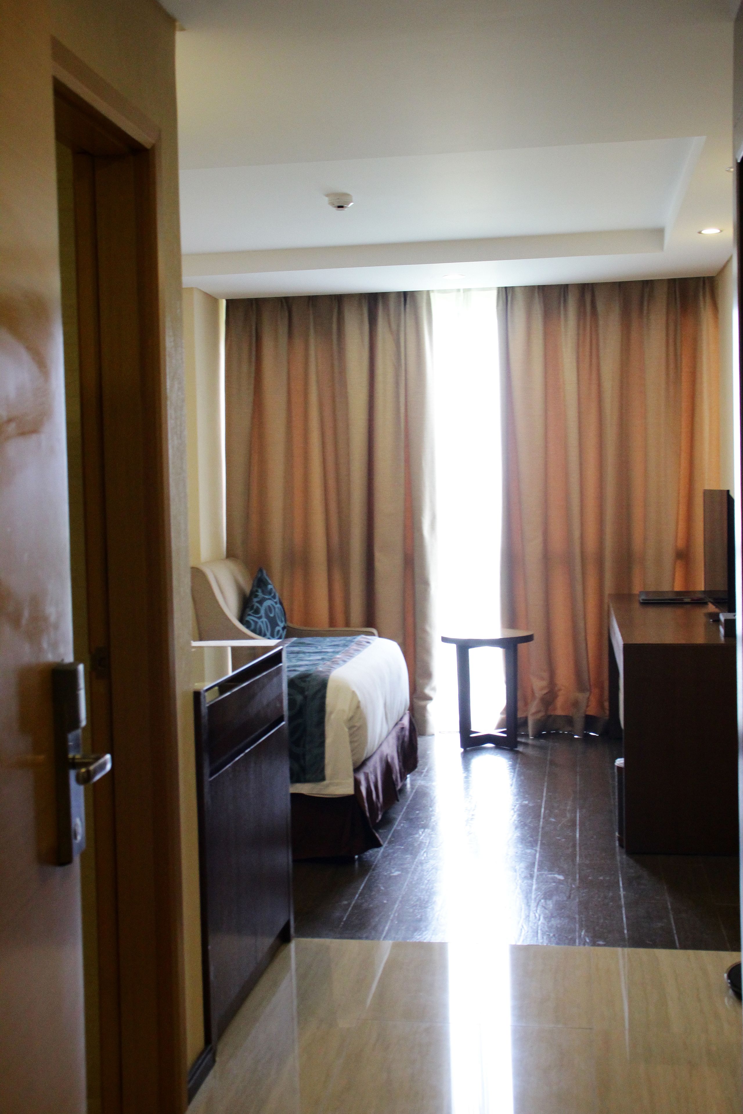 Habitació d'hotel amb un llit, una taula de treball, una cadira i una televisió.