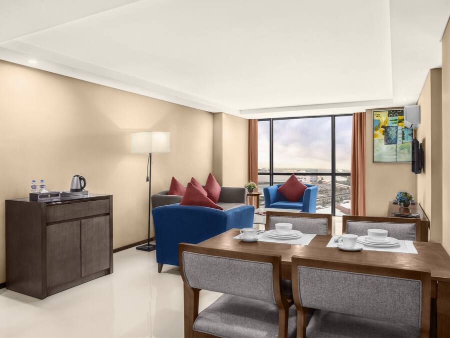 Een moderne hotelkamer met een zithoek, een bank, een bijzettafeltje en uitzicht op de stad.