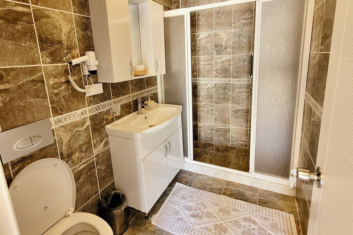 A bathroom with a toilet, sink, and shower area.