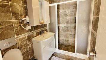 Un baño con inodoro, lavamanos y zona de ducha.