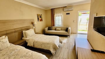 Una habitación de hotel con dos camas, un sofá, un televisor y una ventana con cortinas.