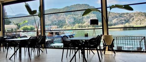 A dining area with large windows overlooking a lake and mountains.