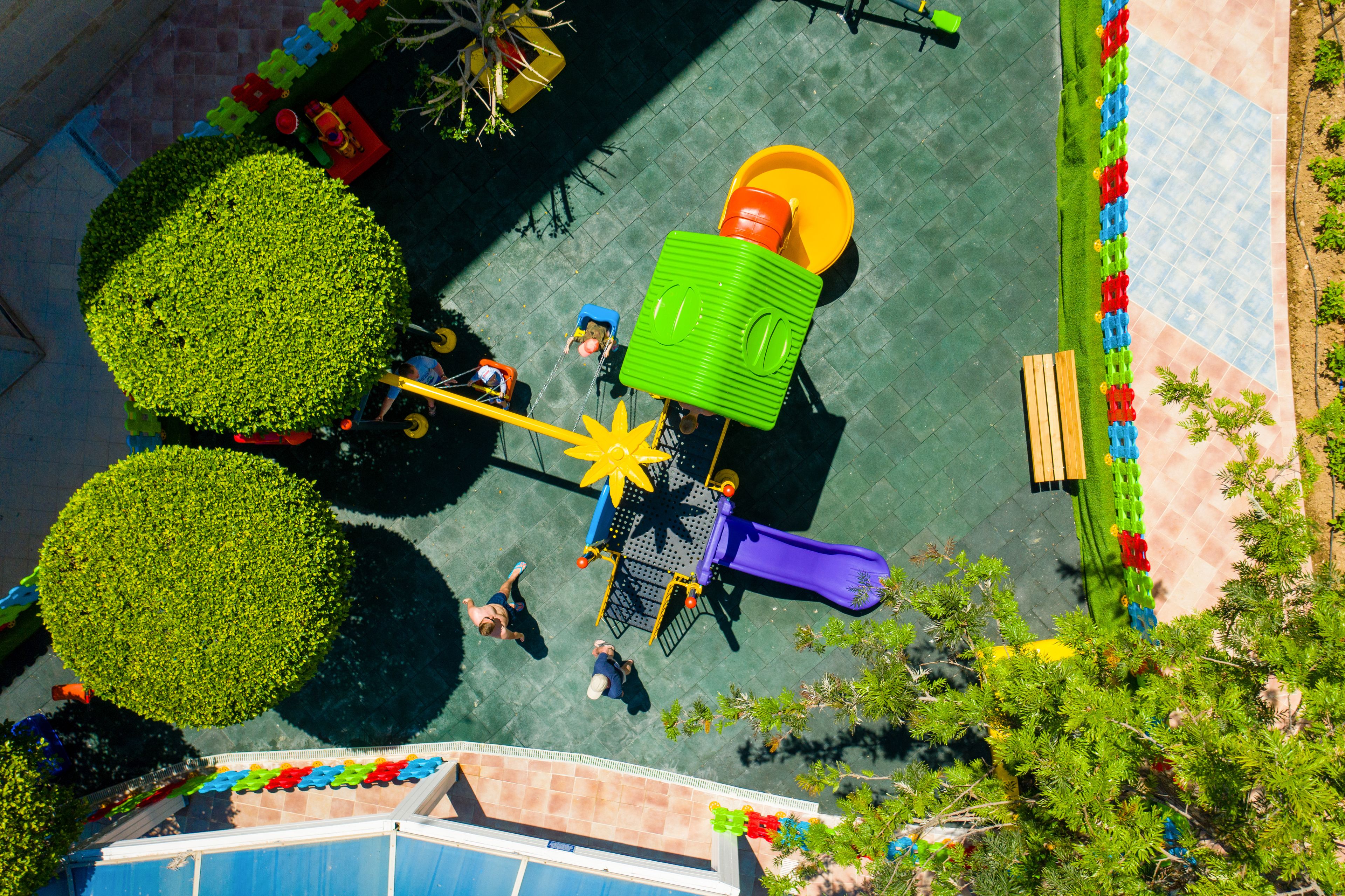 Vista aérea de un parque infantil con tobogán, estructuras para escalar y un área de juegos en forma de estrella amarilla.