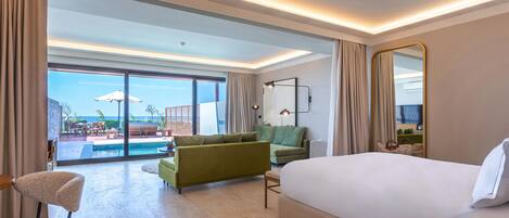 A hotel room with a large bed, a sofa, a chair, a desk, and a view of the pool and outdoor area.