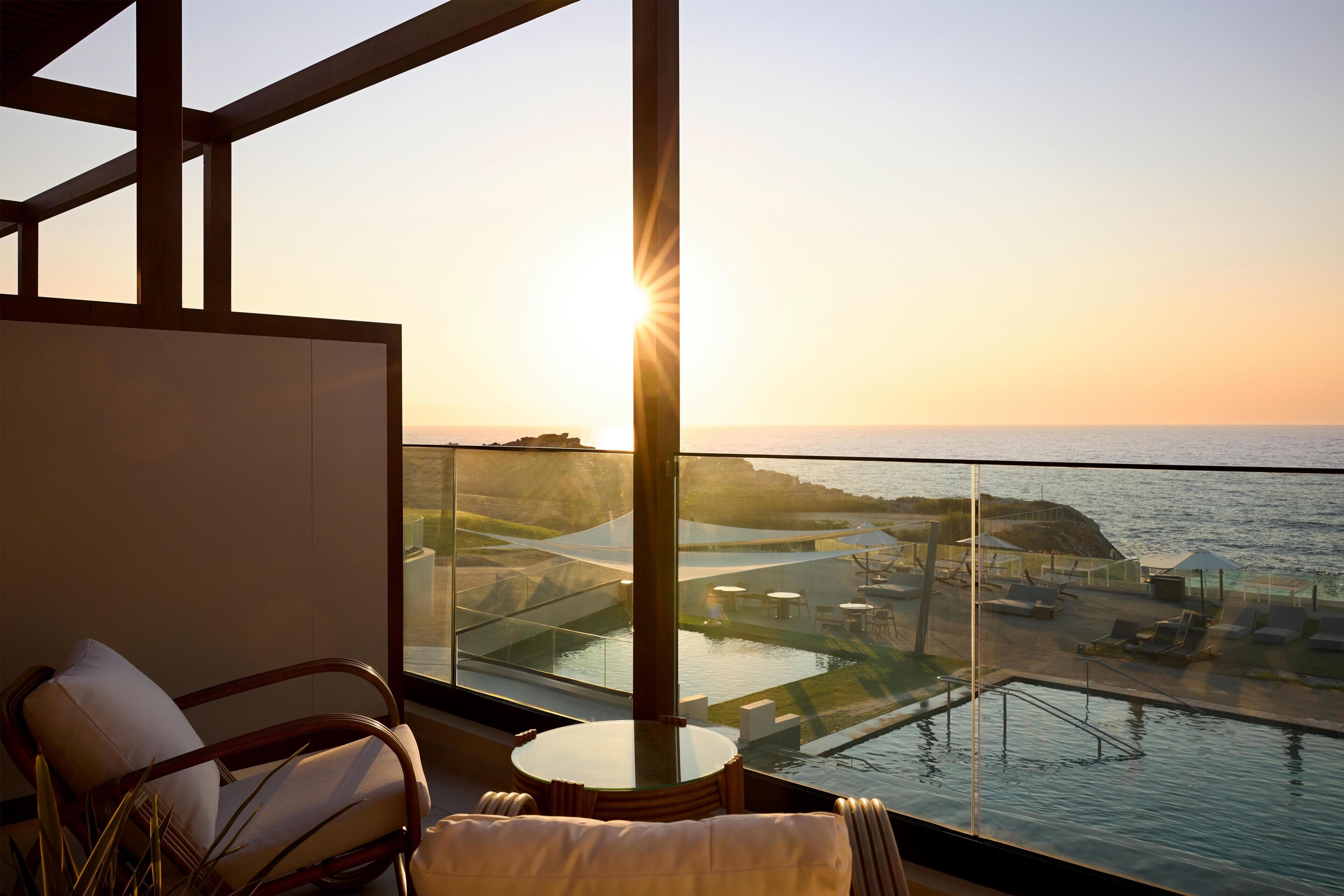 A balcony with a view of the sea and a sunset.