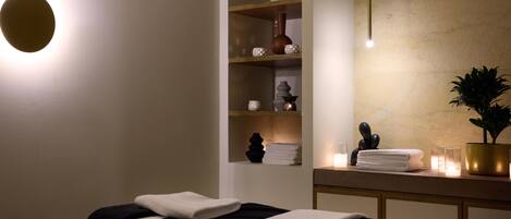 A spa room with a massage table, shelves with decorative items, and a potted plant.