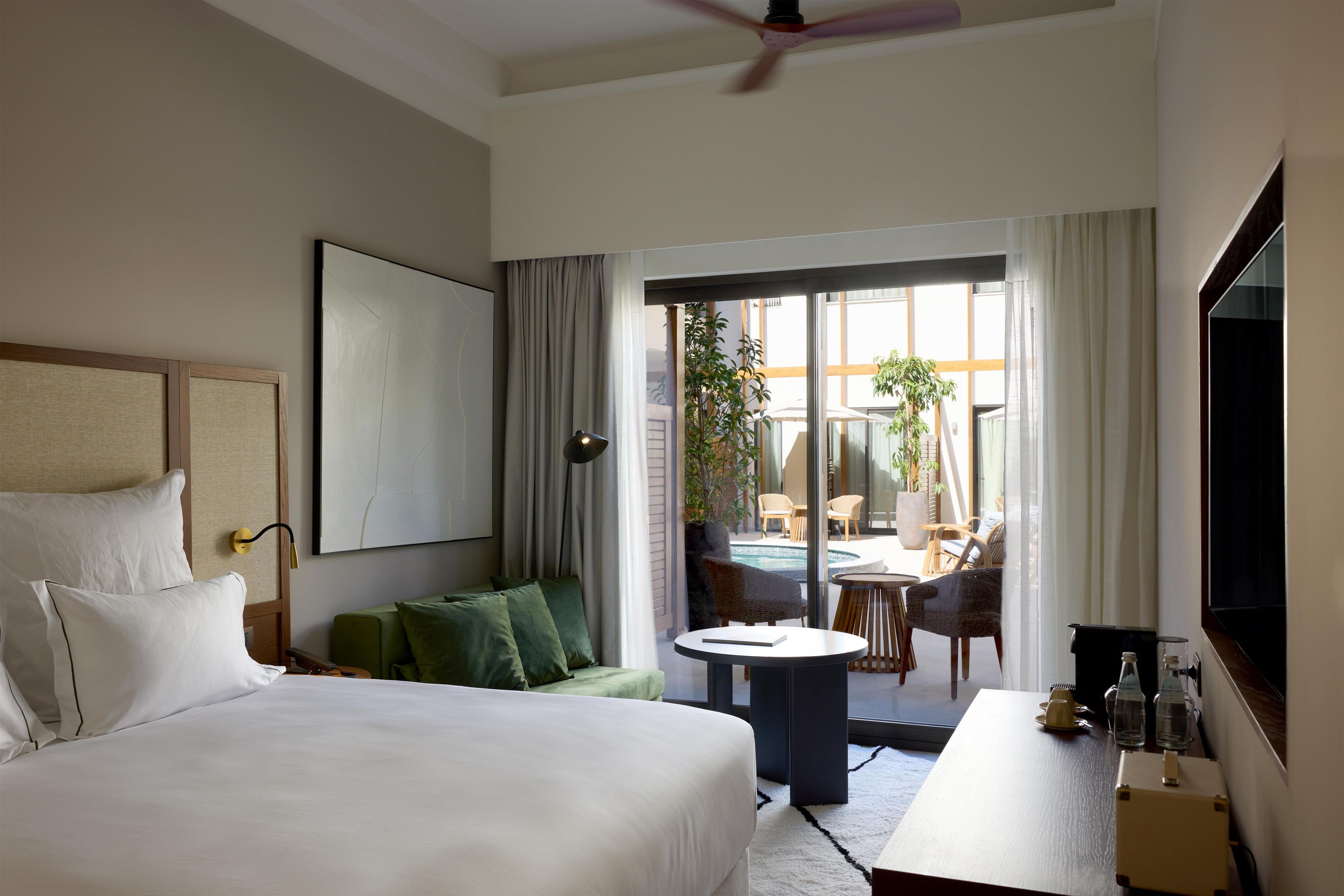 A hotel room with a bed, a sofa, a table, and a view of the outside.