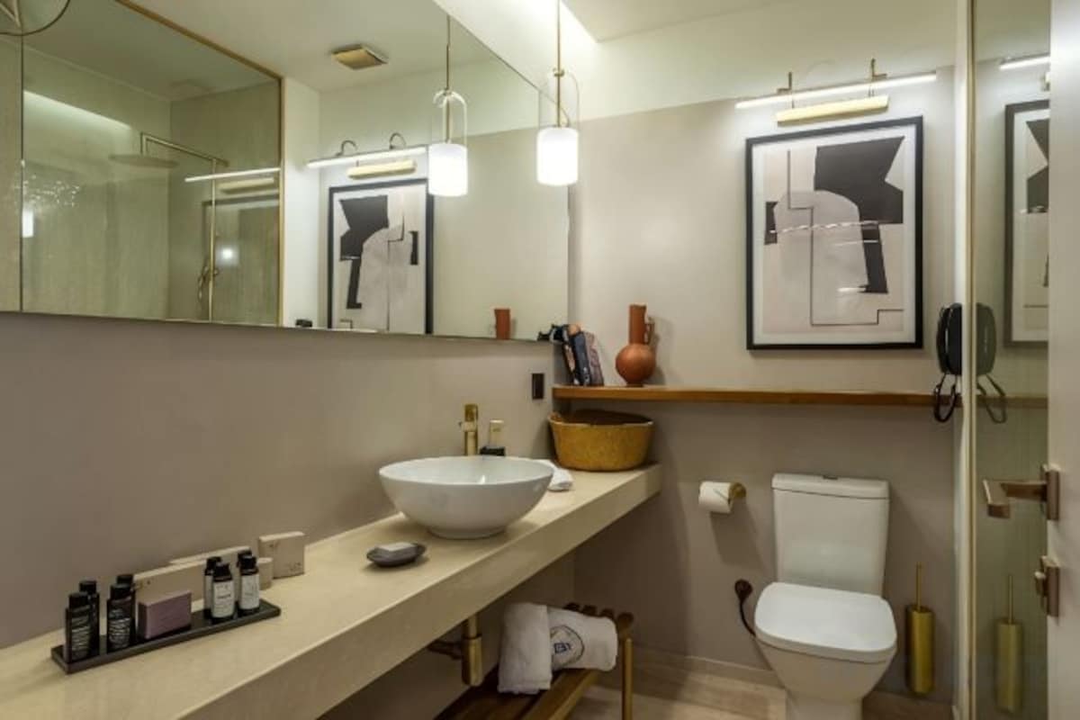 A modern bathroom with a large mirror, a white sink, and a toilet.