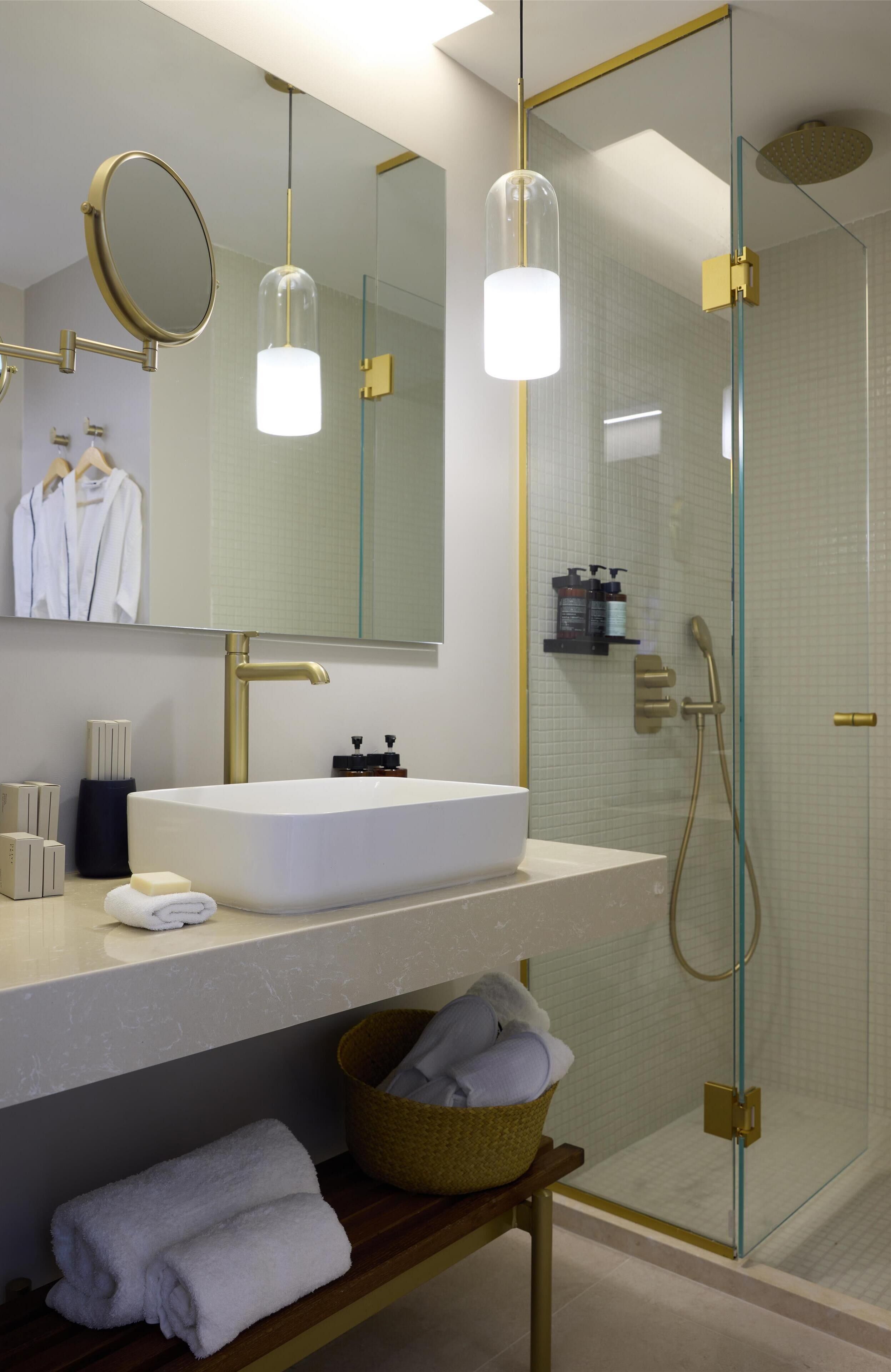 A modern bathroom with a large mirror, a sink, and a glass-enclosed shower.