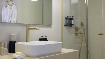 A modern bathroom with a large mirror, a sink, and a glass-enclosed shower.