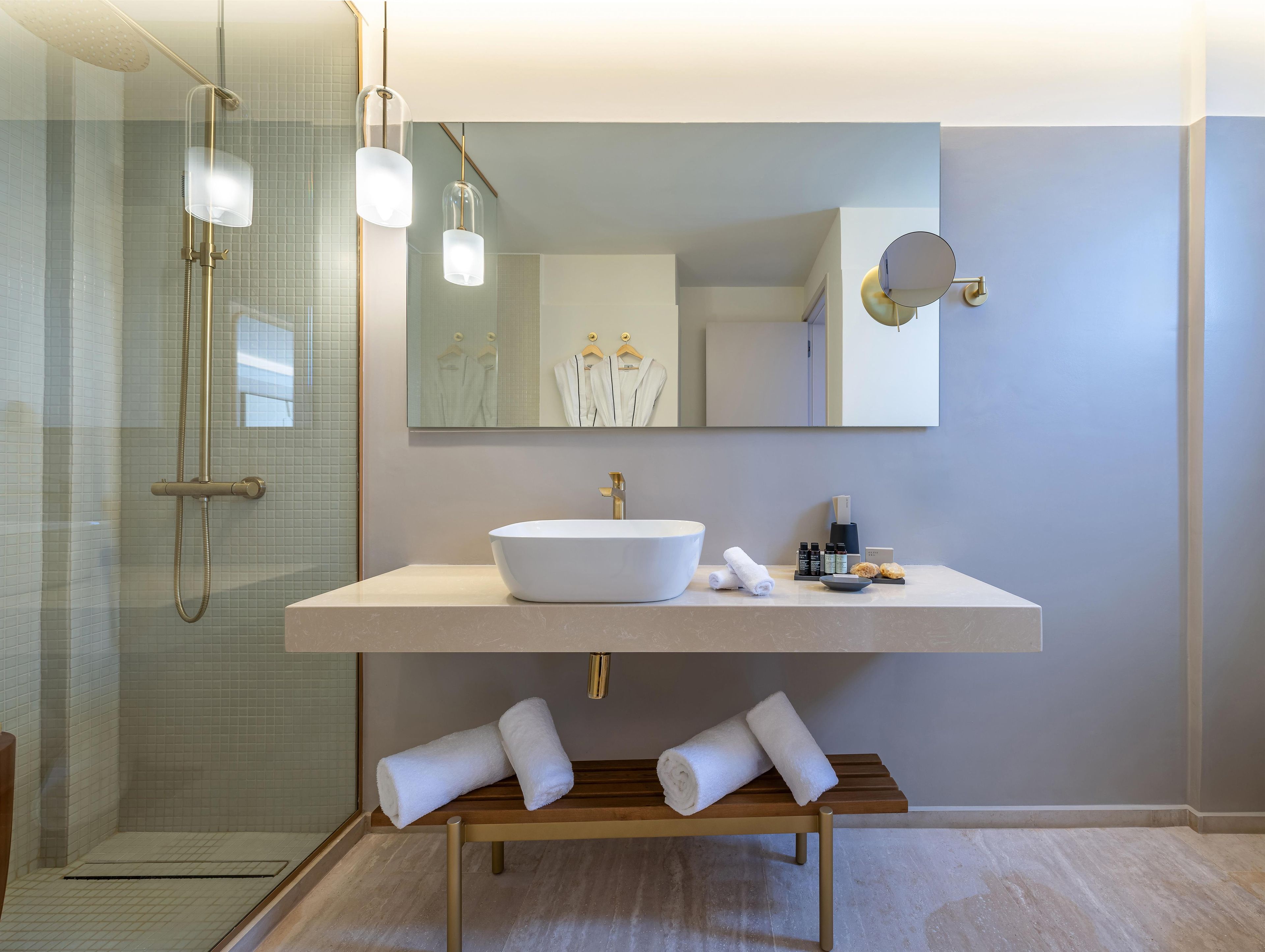A modern bathroom with a large sink, a mirror, and a shower area.