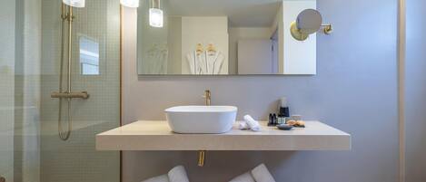 A modern bathroom with a large sink, a mirror, and a shower area.