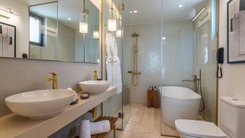 A modern bathroom with a large white sink, a bathtub, and a walk-in shower.