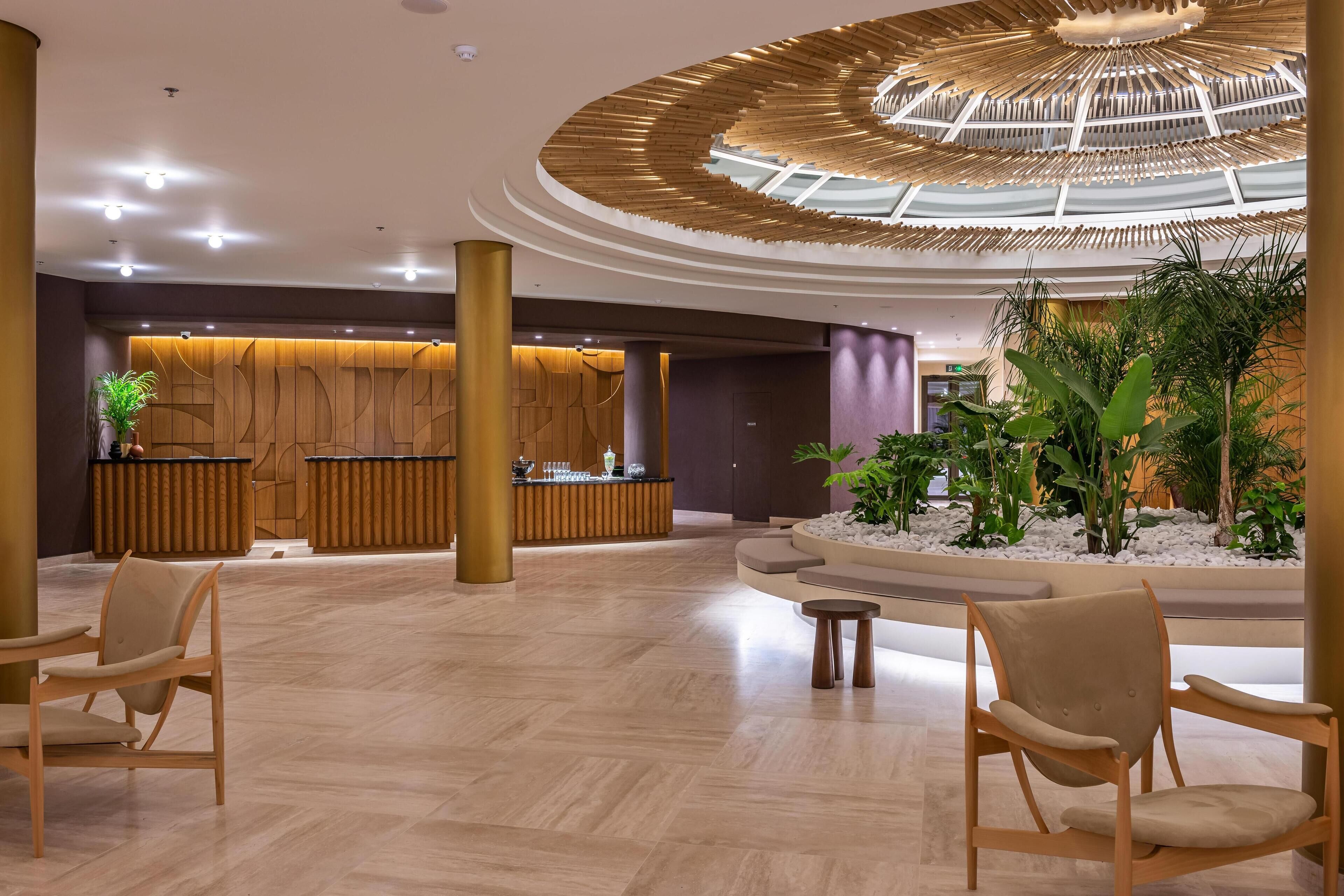 Un vestíbulo amplio con una recepción, zona de estar y un arreglo floral central.