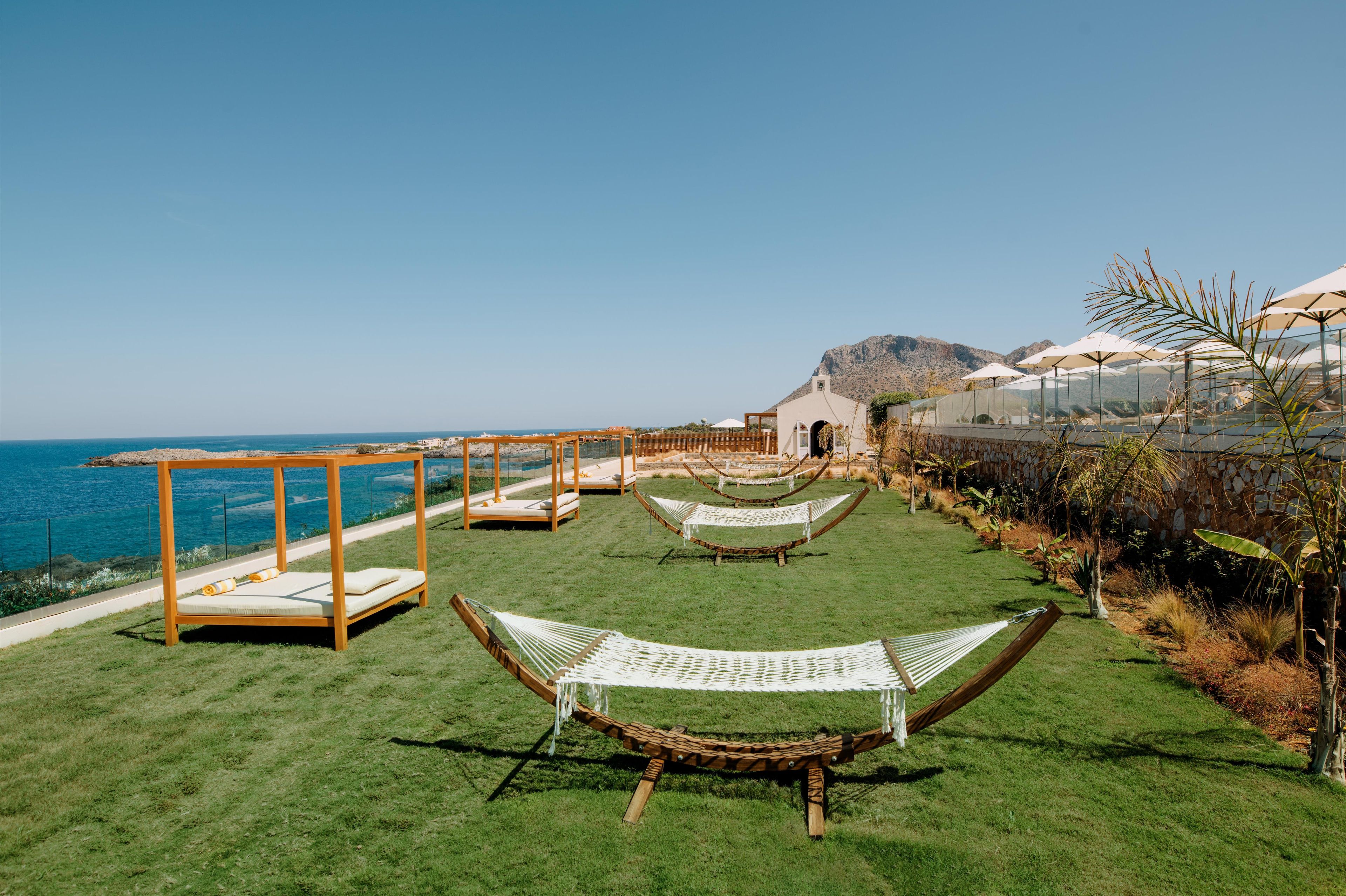 Een gazon met hangmatten en een pergola, met uitzicht op de kust.