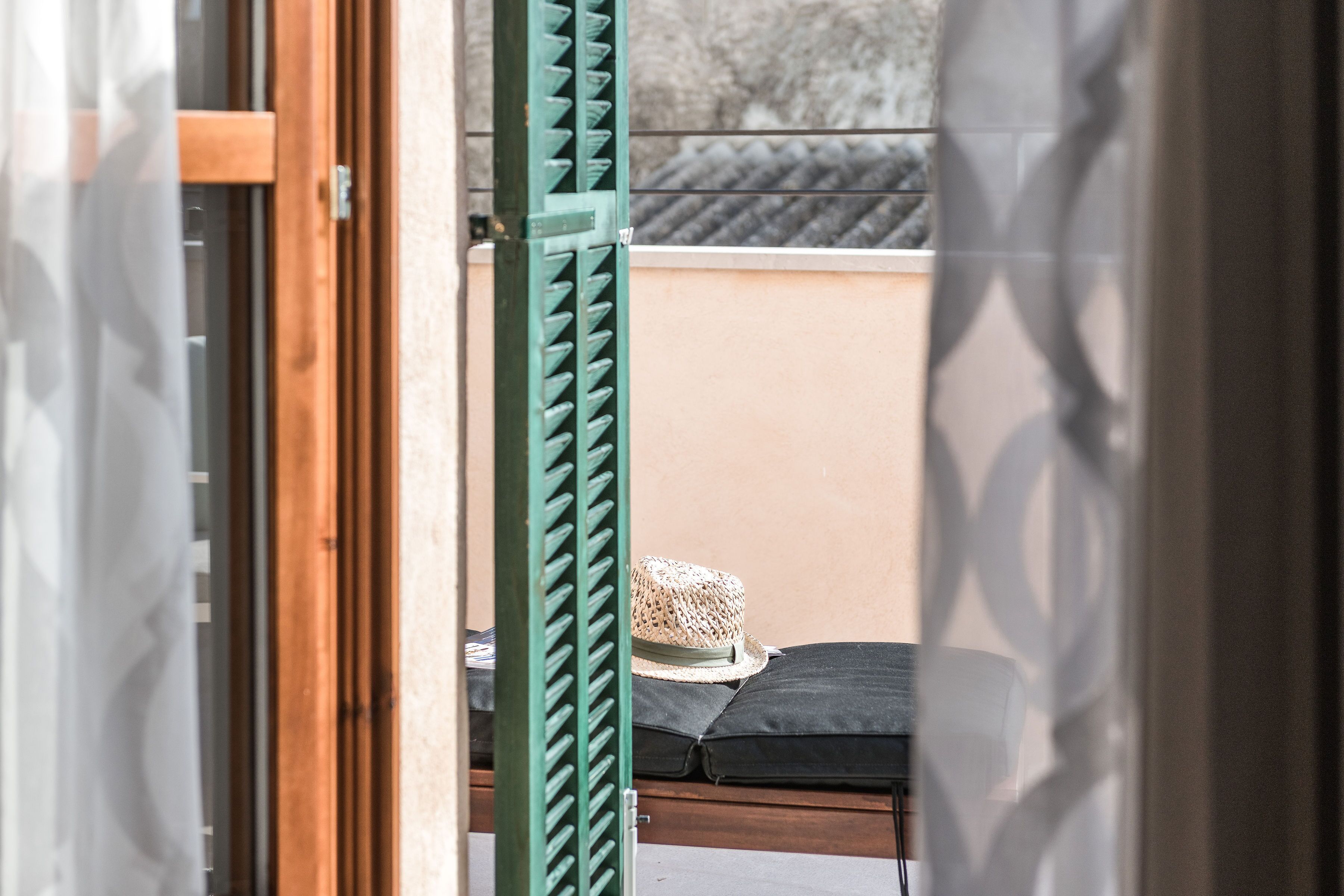 A room with a bed, a green metal gate, and a beige wall.