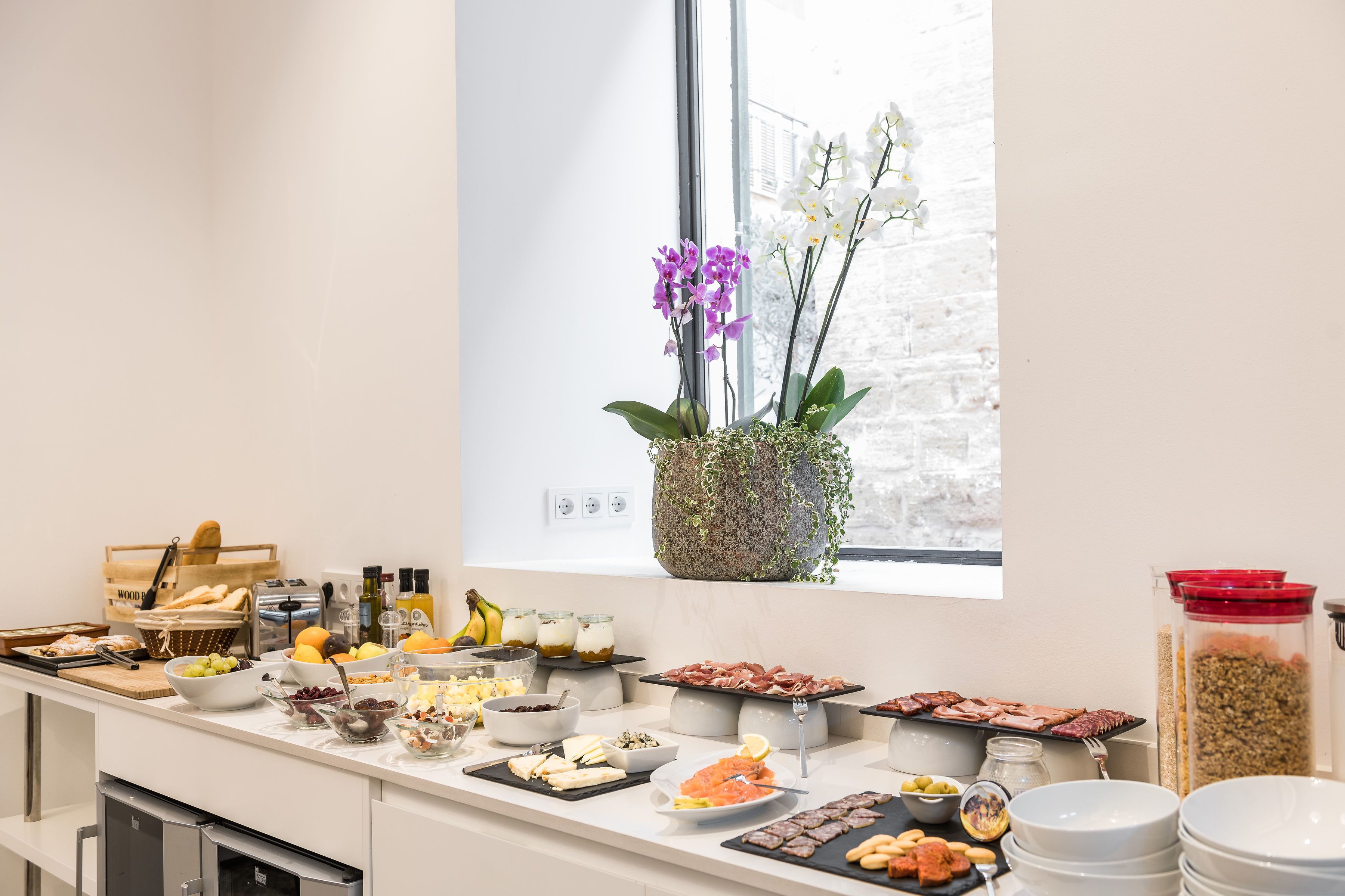 Un buffet garni de divers plats et agrémenté d’une plante décorative près d’une fenêtre.