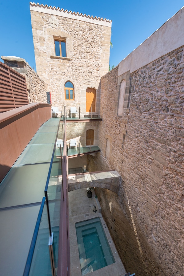 Un edificio de piedra con balcón de vidrio y piscina.