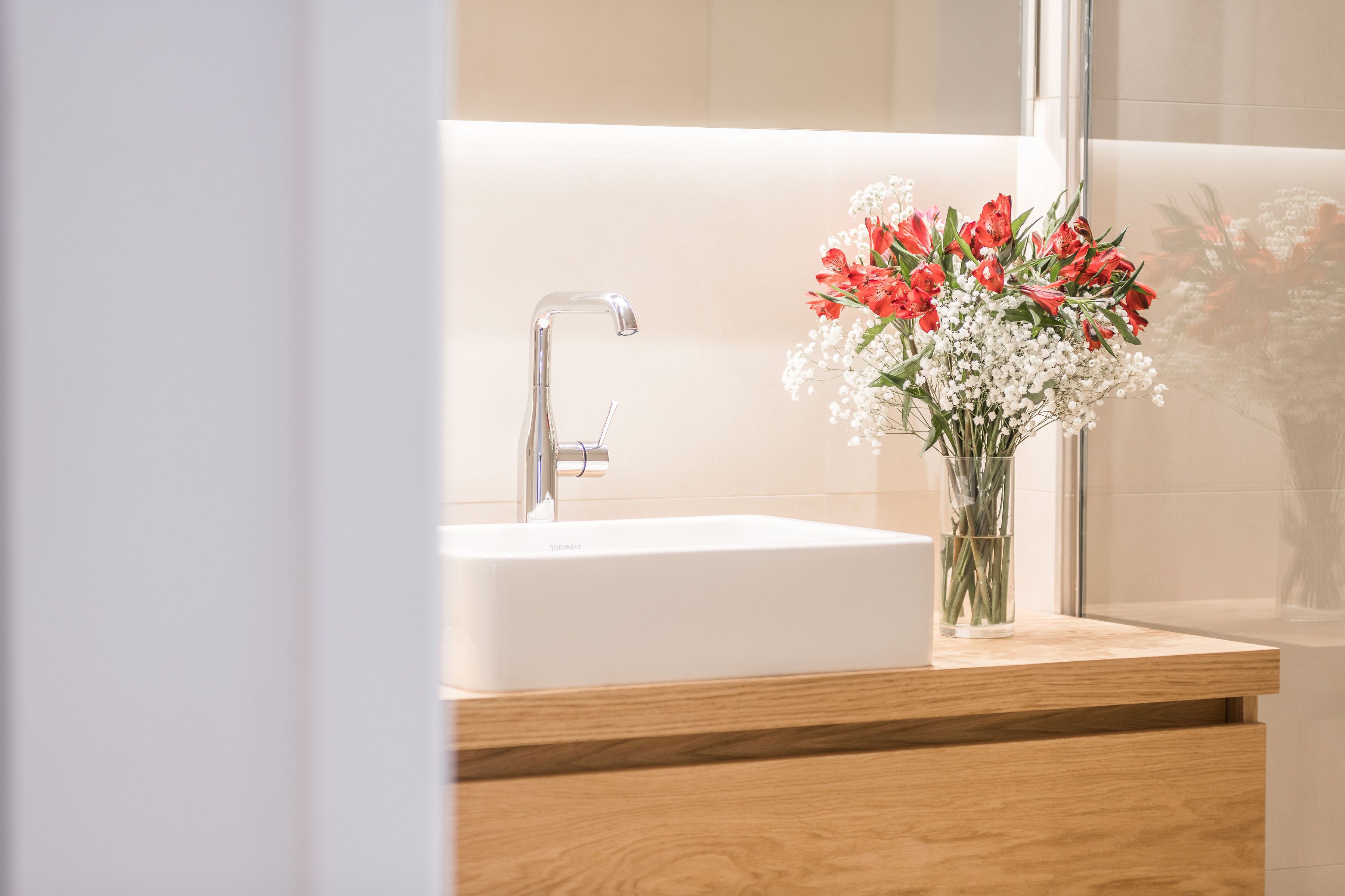 A bathroom with a white sink, a modern faucet, and a wooden vanity.