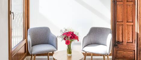 A room with two chairs, a small table, and a vase of flowers.