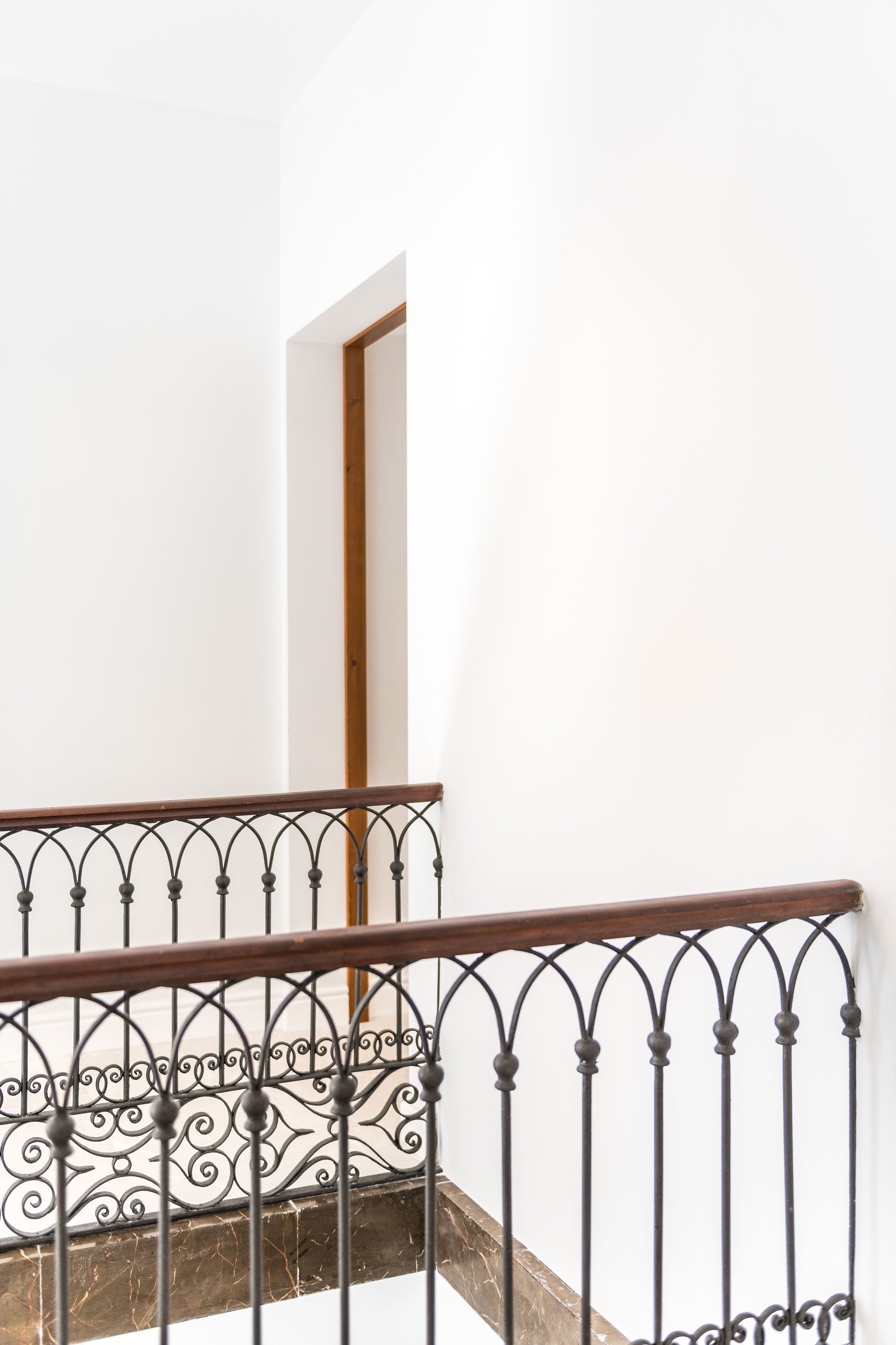 Una escalera con barandilla de hierro forjado y pasamanos de madera.