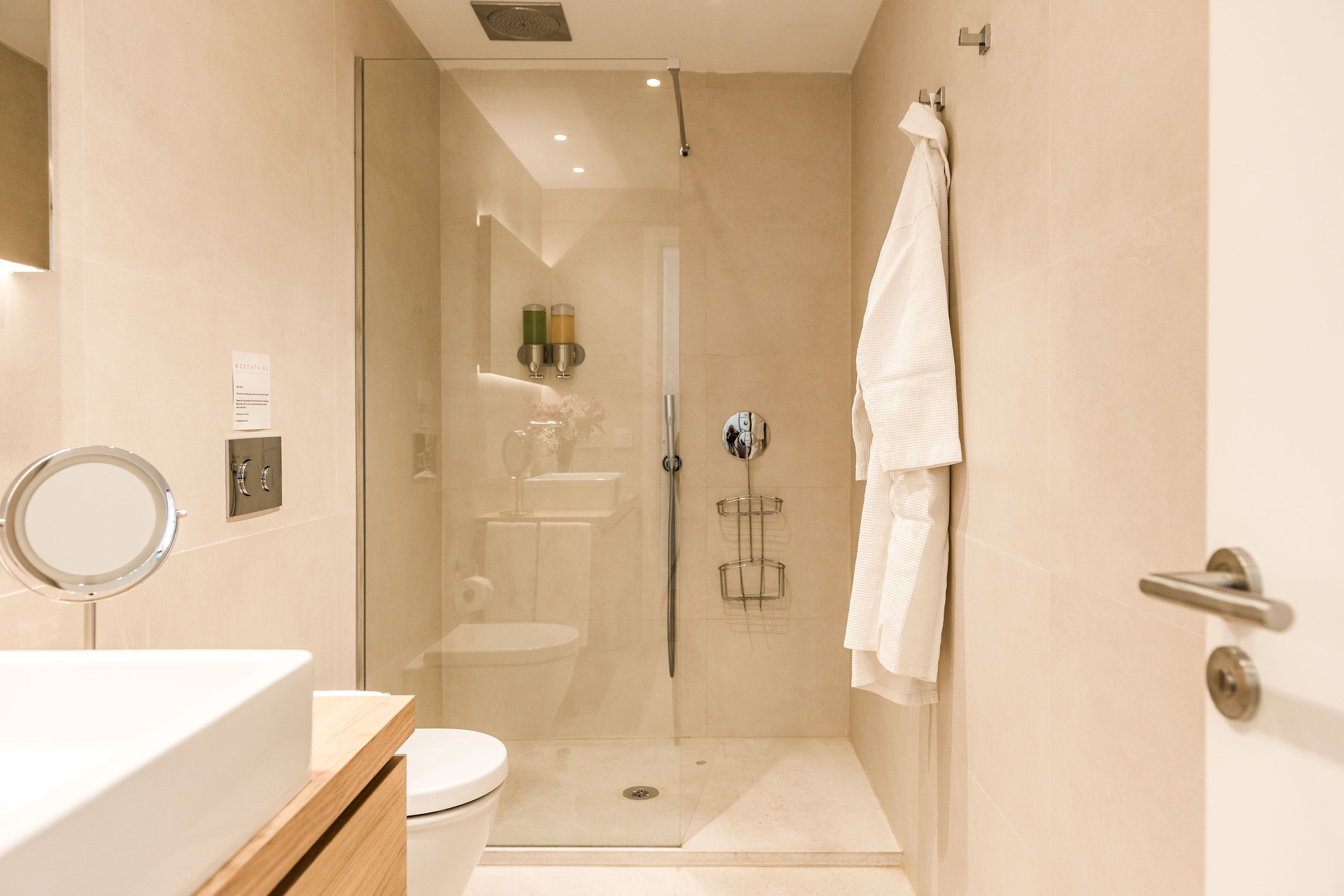A modern bathroom with a glass-enclosed shower, a toilet, and a sink.
