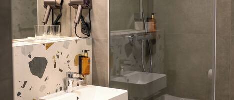 A modern bathroom with a glass-enclosed shower, a white sink, and a mirror with a towel rack.