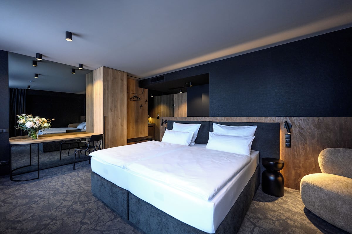 A modern hotel room with a large bed, bedside tables, a desk, and a chair.