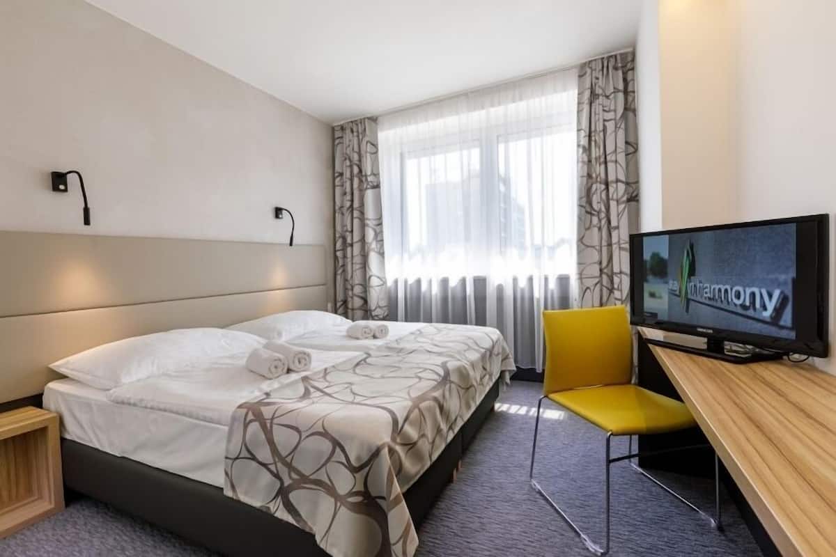 A hotel room with a bed, a TV, a desk, and a chair.