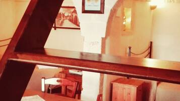 Una habitación con una mesa y sillas de madera, un mueble pequeño y un cuadro en la pared.