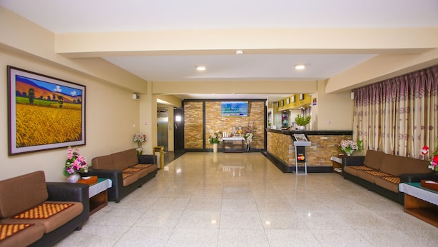 Un vestíbulo de hotel con recepción, zona de estar y un cuadro grande en la pared.