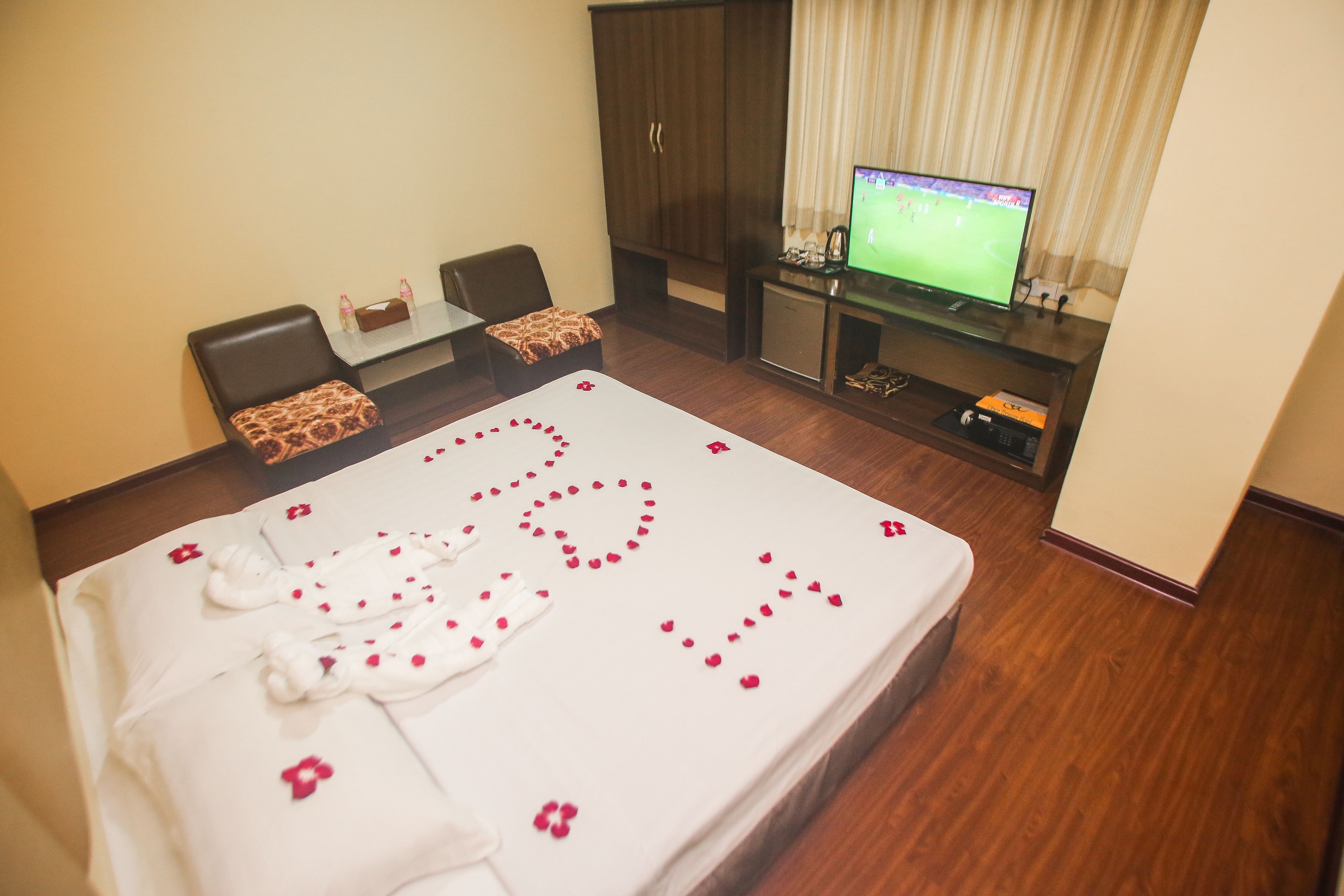 Habitación de hotel con una cama bien hecha, un televisor, un escritorio con silla y un armario.