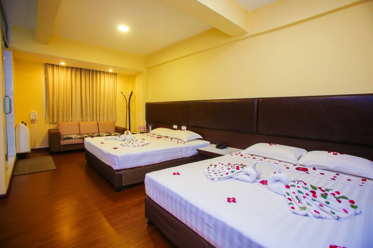 A hotel room with two beds, a sofa, and a desk.