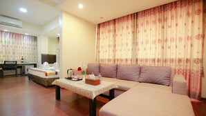 Una habitación de hotel con sofá, mesa de comedor, televisor y escritorio.