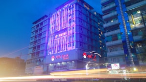 Un edificio de varios pisos con un llamativo letrero de AYA Bank, que indica una zona comercial con servicios bancarios.