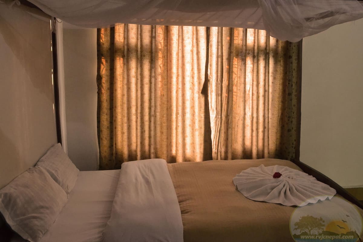 A hotel room with a bed, curtains, and a mosquito net.