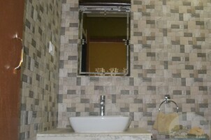 A bathroom with a tiled backsplash, a sink, a mirror, and a towel rack.