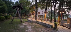 A pathway leading to a building with thatched-roof structures and stone walls. - River View Jungle Camp (Sauraha)