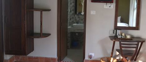 A room with a wooden cabinet, a small table with a mirror, a television, and a basket on the floor.