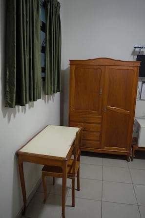 Simple, functional room with a wardrobe, dining table, and window offering a view.