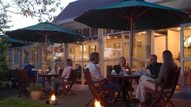 An outdoor seating area with tables and chairs, surrounded by umbrellas and potted plants. - Hotel Smedegaarden (Lem)
