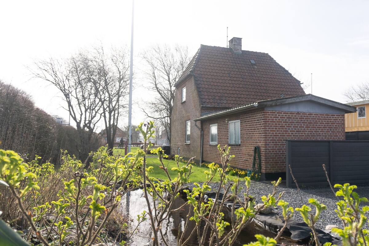 A residential area with houses, a grassy yard, and a gravel path.