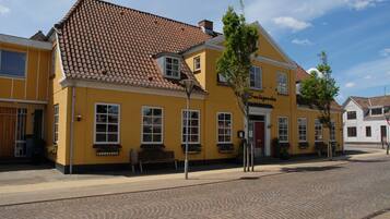 A yellow building with a tiled roof, a bench outside, and a sign that reads "Smedegården".