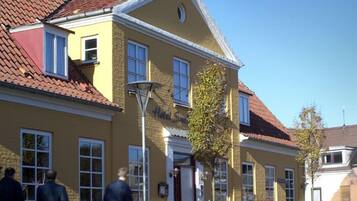 A yellow building with a red-tiled roof, a visible entrance, and a sign that reads "Hotel Svarthuset."