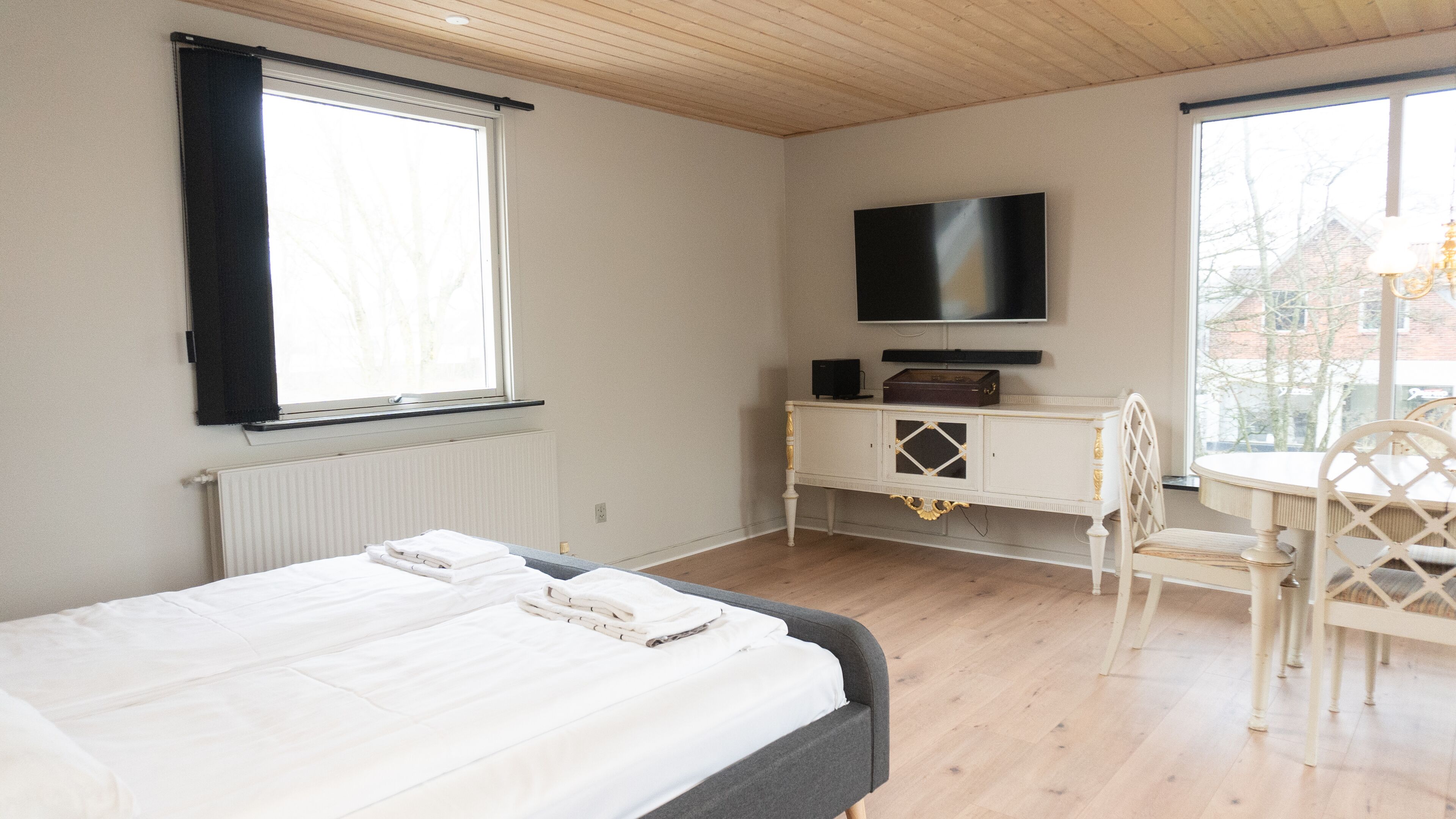 A bedroom with a bed, a TV, a desk, and a chair.
