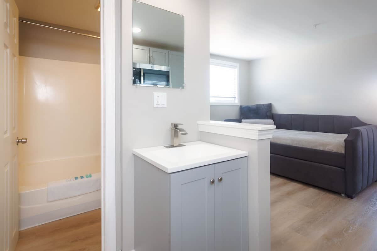 A bathroom with a shower, a sink, and a mirror.