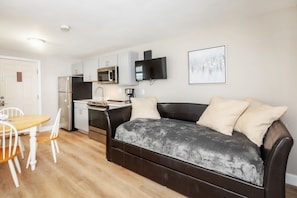 A compact living space with a kitchenette, a sofa, a dining table, and chairs. - Atlantic Motel (Hampton)
