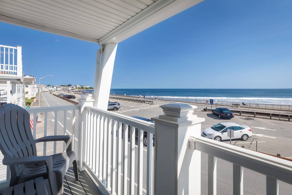 A balcony with a view of the ocean and a road with cars.