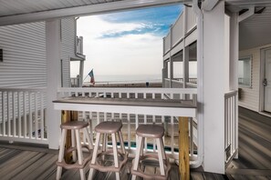 A covered outdoor area with a pool, white railings, and a view of the ocean. - Atlantic Motel (Hampton)