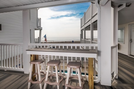 A covered outdoor area with a pool, white railings, and a view of the ocean.. Atlantic Motel